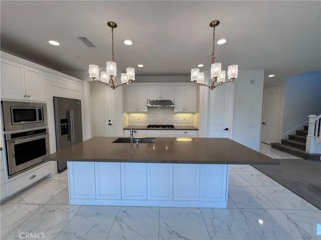 a view of a center island a chandelier and kitchen view