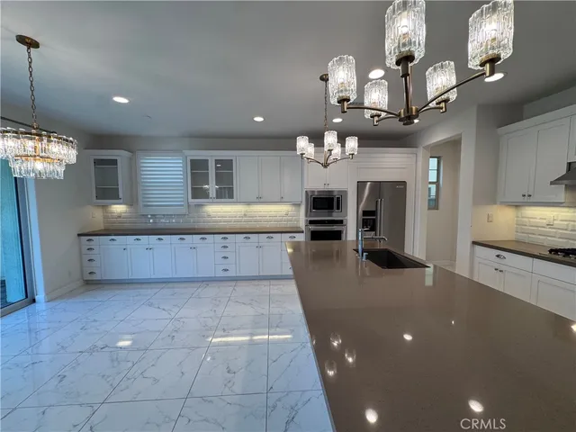 a large kitchen with granite countertop a sink counter top space appliances and cabinets