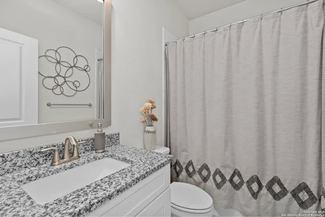 a bathroom with a granite countertop sink and a mirror