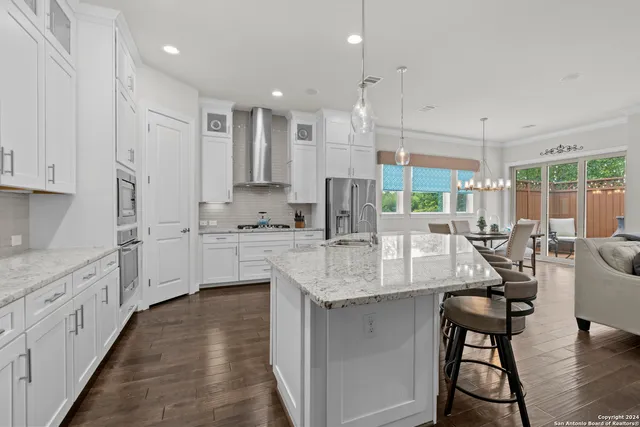 a kitchen with stainless steel appliances granite countertop a stove top oven a sink island and white cabinets