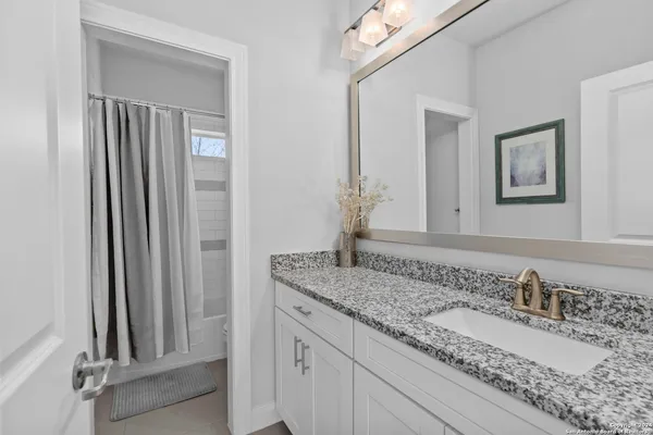 a bathroom with a granite countertop sink and a mirror