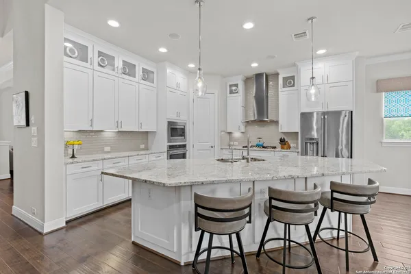 a kitchen with stainless steel appliances granite countertop white cabinets and chairs