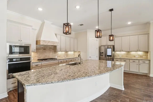 a kitchen with stainless steel appliances granite countertop a sink a stove and a wooden floor