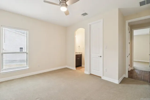 an empty room with chandelier fan and windows