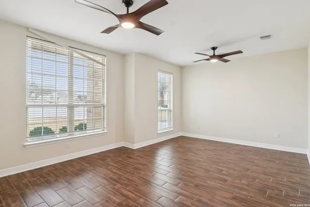 a view of an empty room with a window and wooden floor