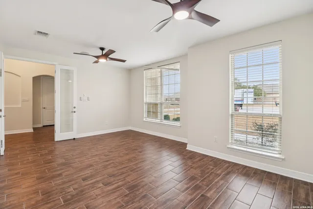 a view of an empty room with a window and wooden floor