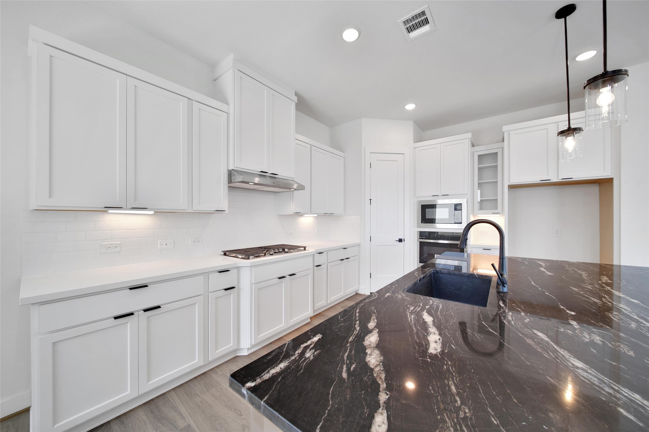 4404 Anthony Court Lane Seabrook, TX 77586 - Photo 8 of 36 a kitchen with stainless steel appliances granite countertop a stove a sink dishwasher and white cabinets with wooden floor