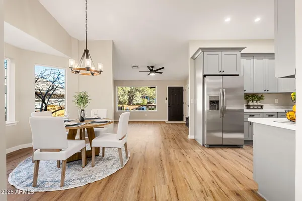 a kitchen with stainless steel appliances granite countertop a refrigerator a stove a sink dishwasher a dining table and chairs with wooden floor