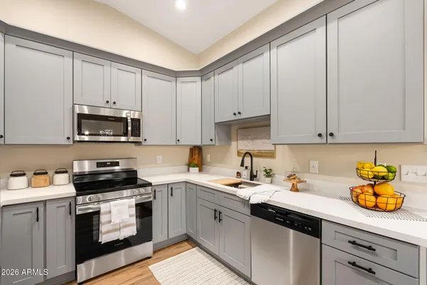 a kitchen with granite countertop white cabinets white stainless steel appliances and a sink