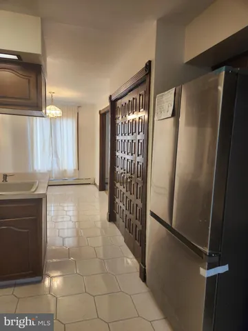 a view of a refrigerator in kitchen and an empty room in wooden floor
