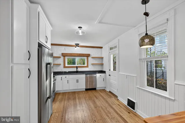a kitchen with granite countertop a stove a sink and a refrigerator