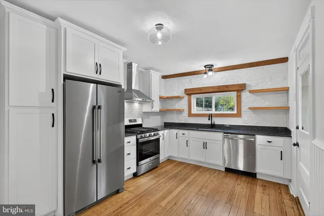 a kitchen with granite countertop a refrigerator stove and sink