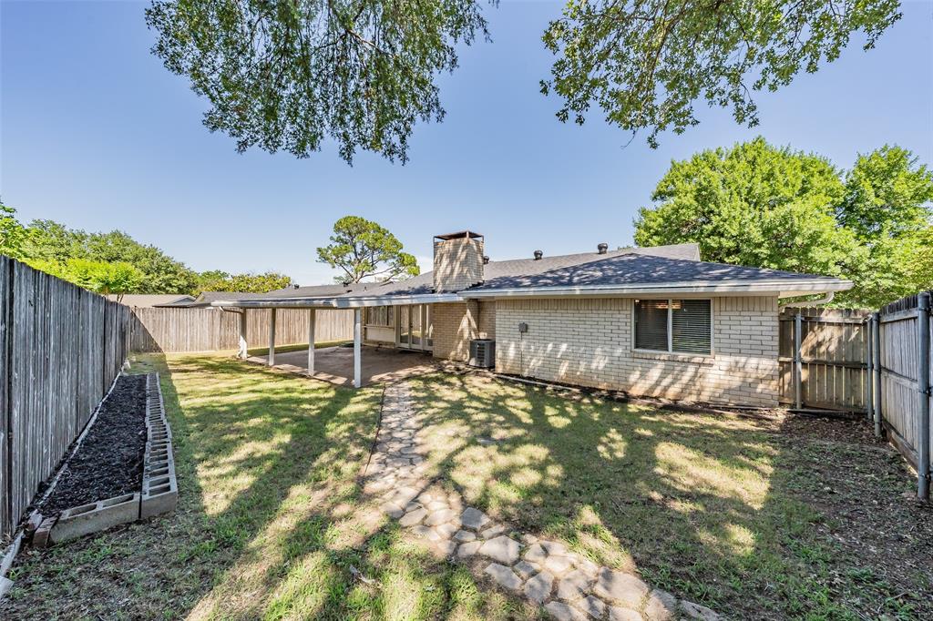 1301 Cedar Ridge Terrace Euless, TX 76039 - Photo 29 of 31 Expansive backyard featuring a covered patio, stone paver pathway, brick exterior, and full privacy fencing