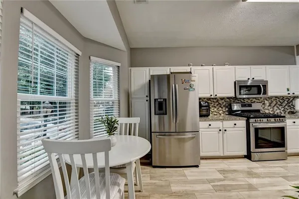 a kitchen with stainless steel appliances a refrigerator a stove a sink dishwasher a dining table and chairs with wooden floor