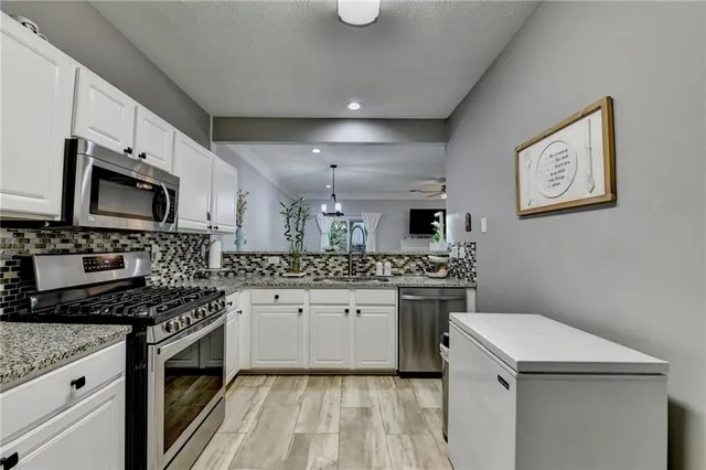 a kitchen with granite countertop a sink a stove and cabinets