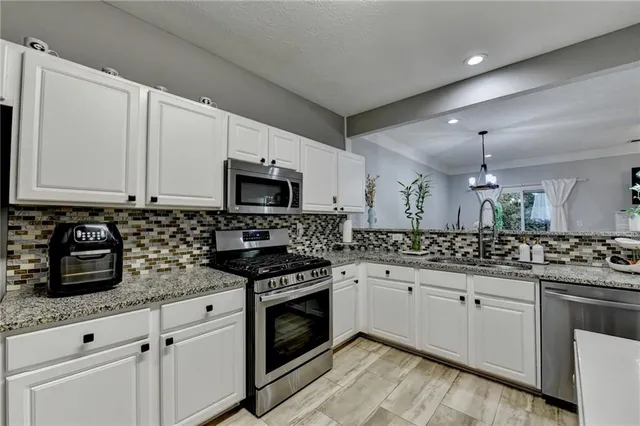 a kitchen with granite countertop white cabinets and white stove