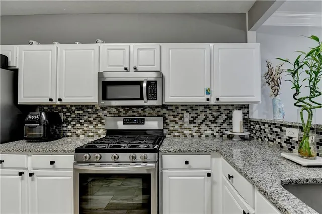 a kitchen with granite countertop a refrigerator stove and microwave