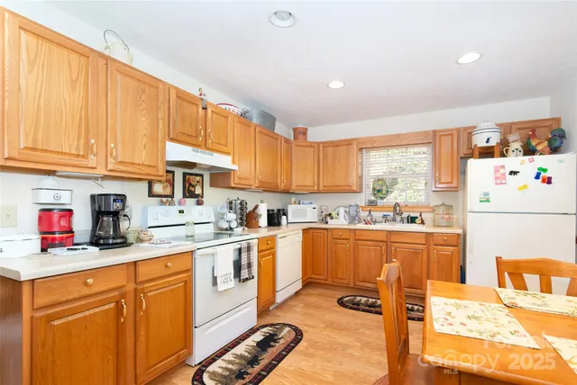 a kitchen with stainless steel appliances granite countertop a stove a sink dishwasher and white cabinets with wooden floor