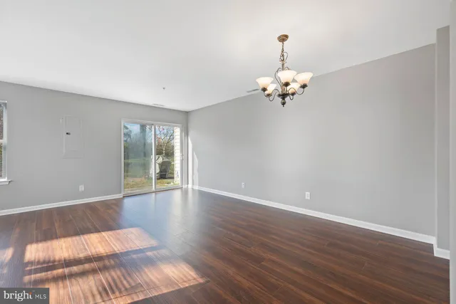 a view of a room with wooden floor chandelier and windows