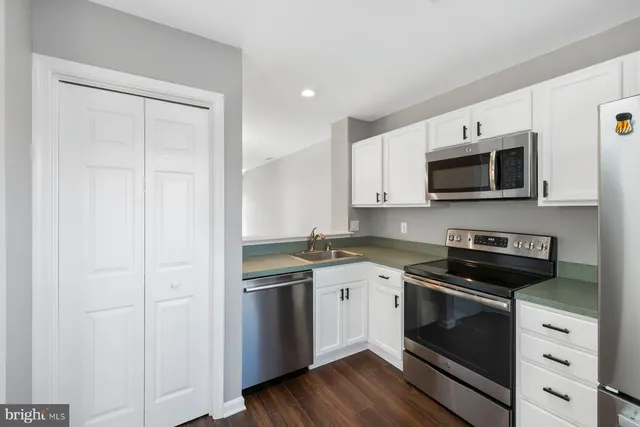 a kitchen with stainless steel appliances granite countertop a stove a microwave and white cabinets