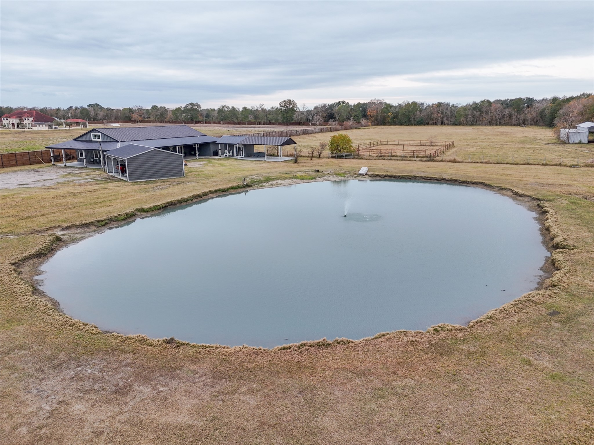 10630 Padon Road Needville, TX 77461 - Photo 1 of 50 Signature aerial view showcases the pond with active fountain framed by open pasture, with the home and covered outdoor living areas positioned just beyond. The layout highlights usable acreage, thoughtful placement of improvements, and the property’s scenic setting.