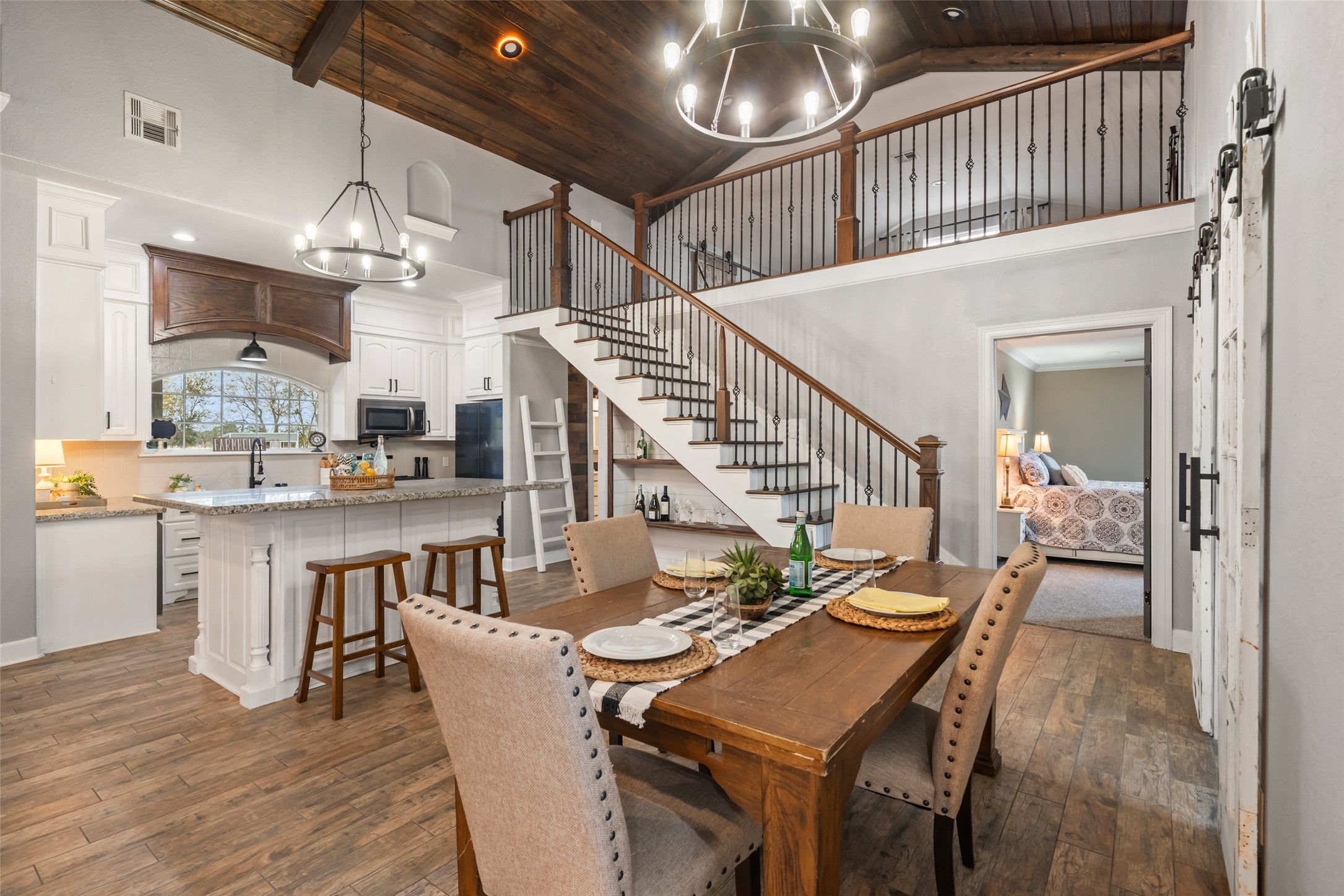 10630 Padon Road Needville, TX 77461 - Photo 11 of 50 Dining area sits beneath vaulted ceilings and statement lighting, with easy access to the kitchen and living spaces. Open rail staircase adds architectural interest.