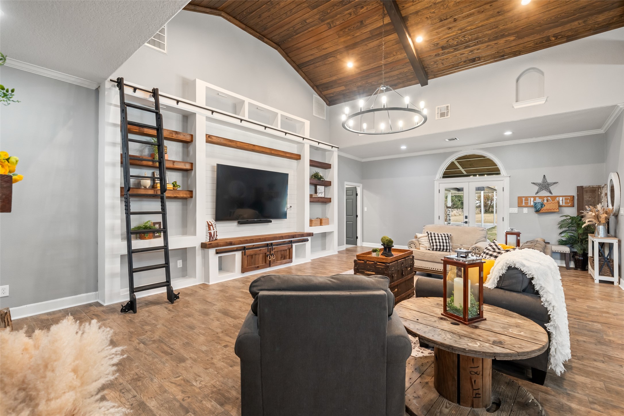 10630 Padon Road Needville, TX 77461 - Photo 14 of 50 Custom built-in media wall features open shelving, ladder access, and integrated storage. The design blends function with architectural detail.