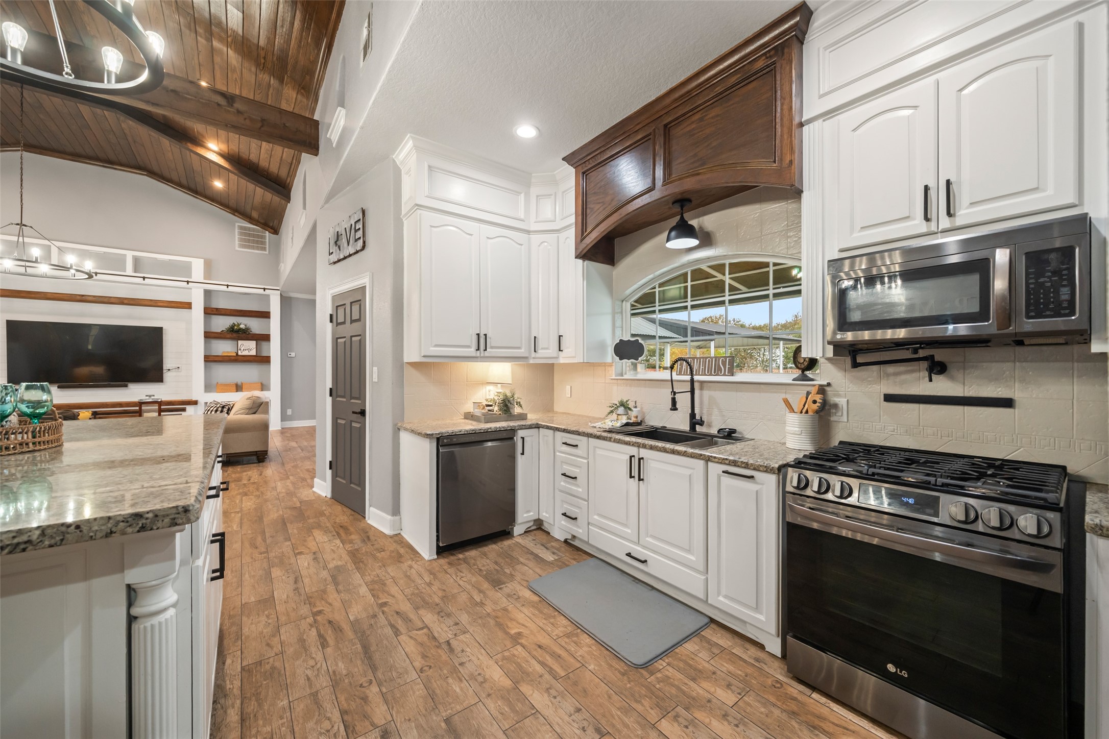 10630 Padon Road Needville, TX 77461 - Photo 16 of 50 Kitchen view highlights granite counters, farmhouse-style sink, gas range, and stainless appliances. The layout maintains connection to the main living area while offering defined workspace.