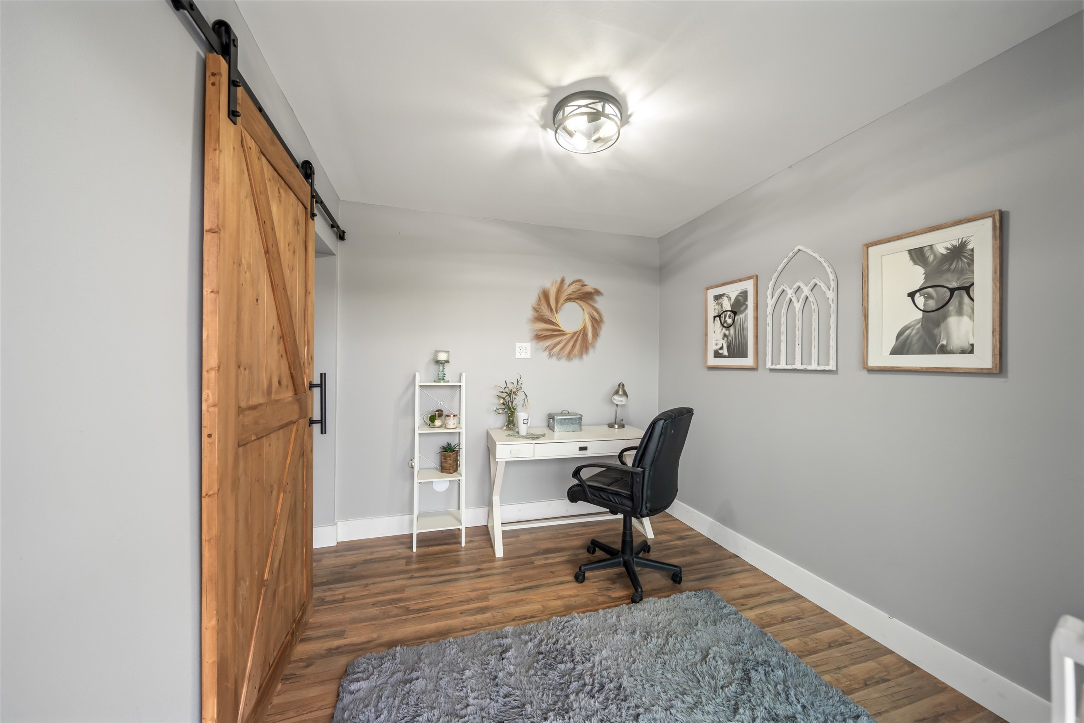 10630 Padon Road Needville, TX 77461 - Photo 17 of 50 Dedicated office or flex room features a sliding barn door, wood-look flooring, and neutral paint. A well-sized layout supports work-from-home or hobby use.