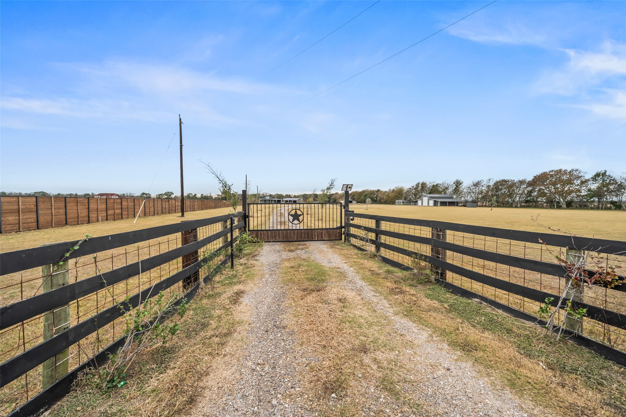 10630 Padon Road Needville, TX 77461 - Photo 2 of 50 Gated entrance with a long gravel drive creates a defined arrival and sets the tone for the expansive property beyond. Fencing on both sides provides structure while maintaining open sightlines.