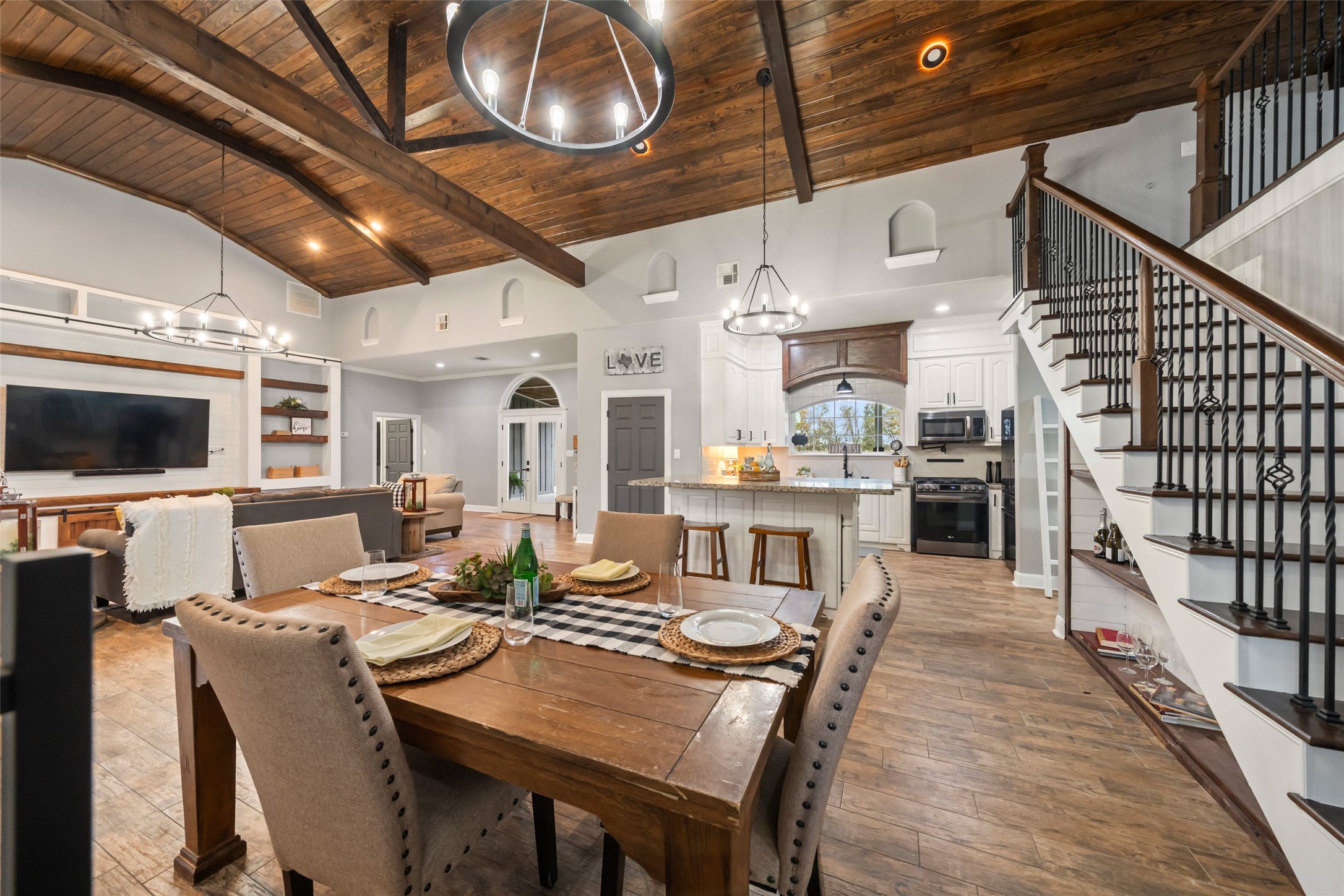 10630 Padon Road Needville, TX 77461 - Photo 22 of 50 Open dining and kitchen view highlights the cohesive layout under vaulted ceilings. Staircase with iron railing adds architectural detail.