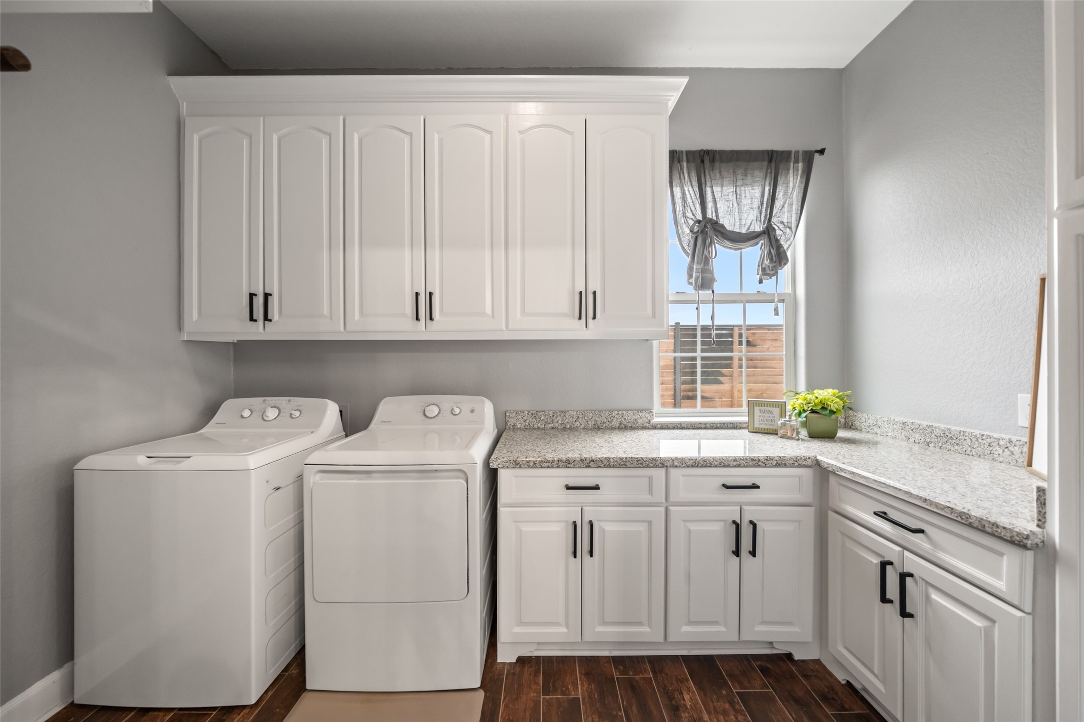 10630 Padon Road Needville, TX 77461 - Photo 27 of 50 Laundry room includes granite countertops, upper and lower cabinetry, and space for full-size washer and dryer. Natural light enhances functionality.