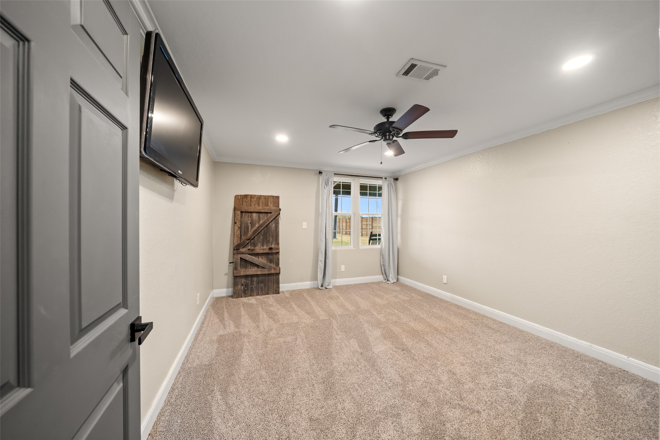 10630 Padon Road Needville, TX 77461 - Photo 29 of 50 Secondary bedroom offers plush carpet, ceiling fan, recessed lighting, and neutral finishes. A barn-style door adds visual interest.