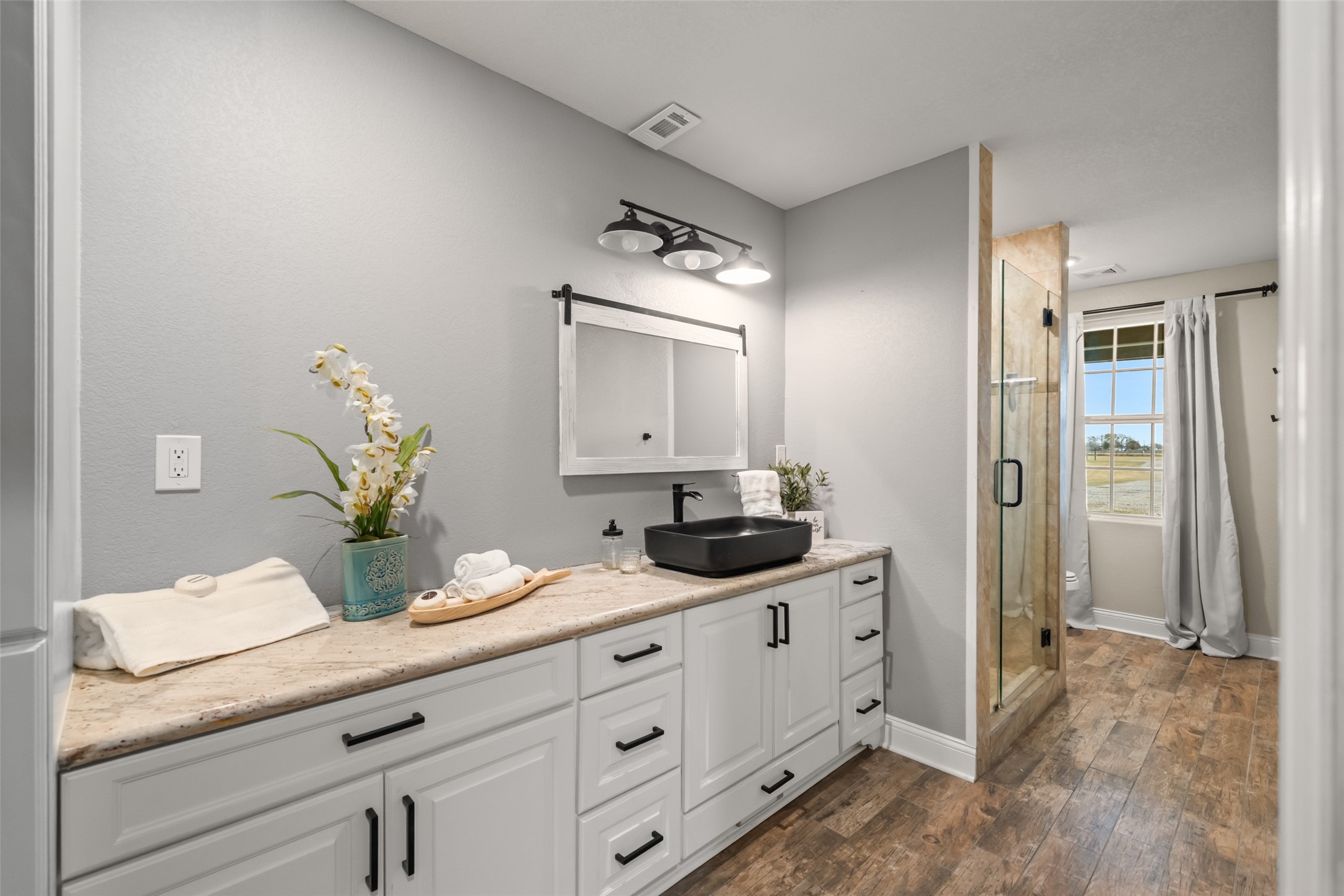 10630 Padon Road Needville, TX 77461 - Photo 30 of 50 Secondary bathroom features a granite-topped vanity, vessel sink, and modern lighting. Walk-in tiled shower and wood-look flooring provide continuity and durability.
