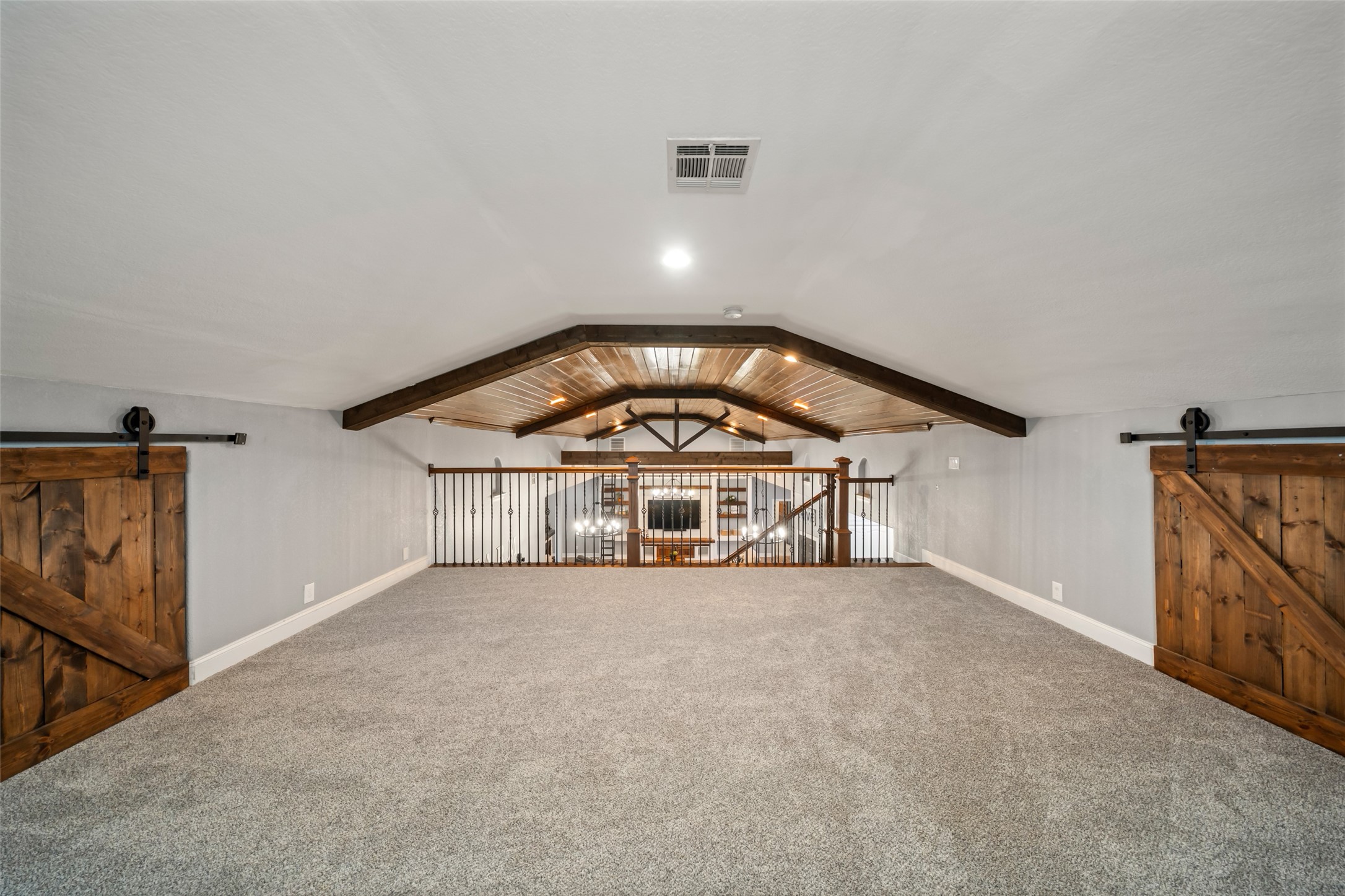 10630 Padon Road Needville, TX 77461 - Photo 34 of 50 Upstairs loft offers a spacious flex area with plush carpet, vaulted ceiling, and exposed wood beams. Open railing overlooks the main living area below.