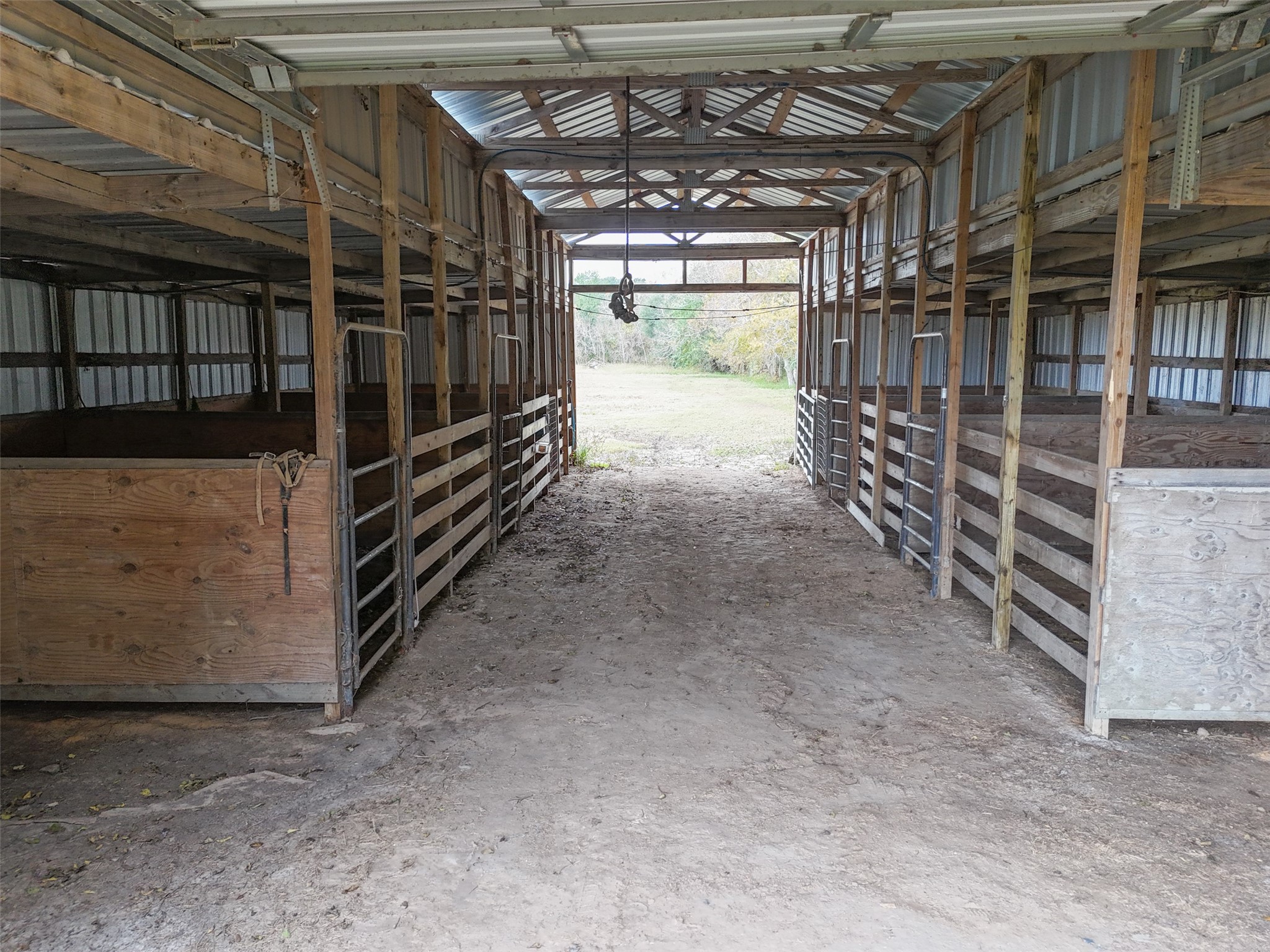 10630 Padon Road Needville, TX 77461 - Photo 41 of 50 Interior view of the barn shows multiple stalls with center aisle access. Wood construction and open layout support practical day-to-day use.