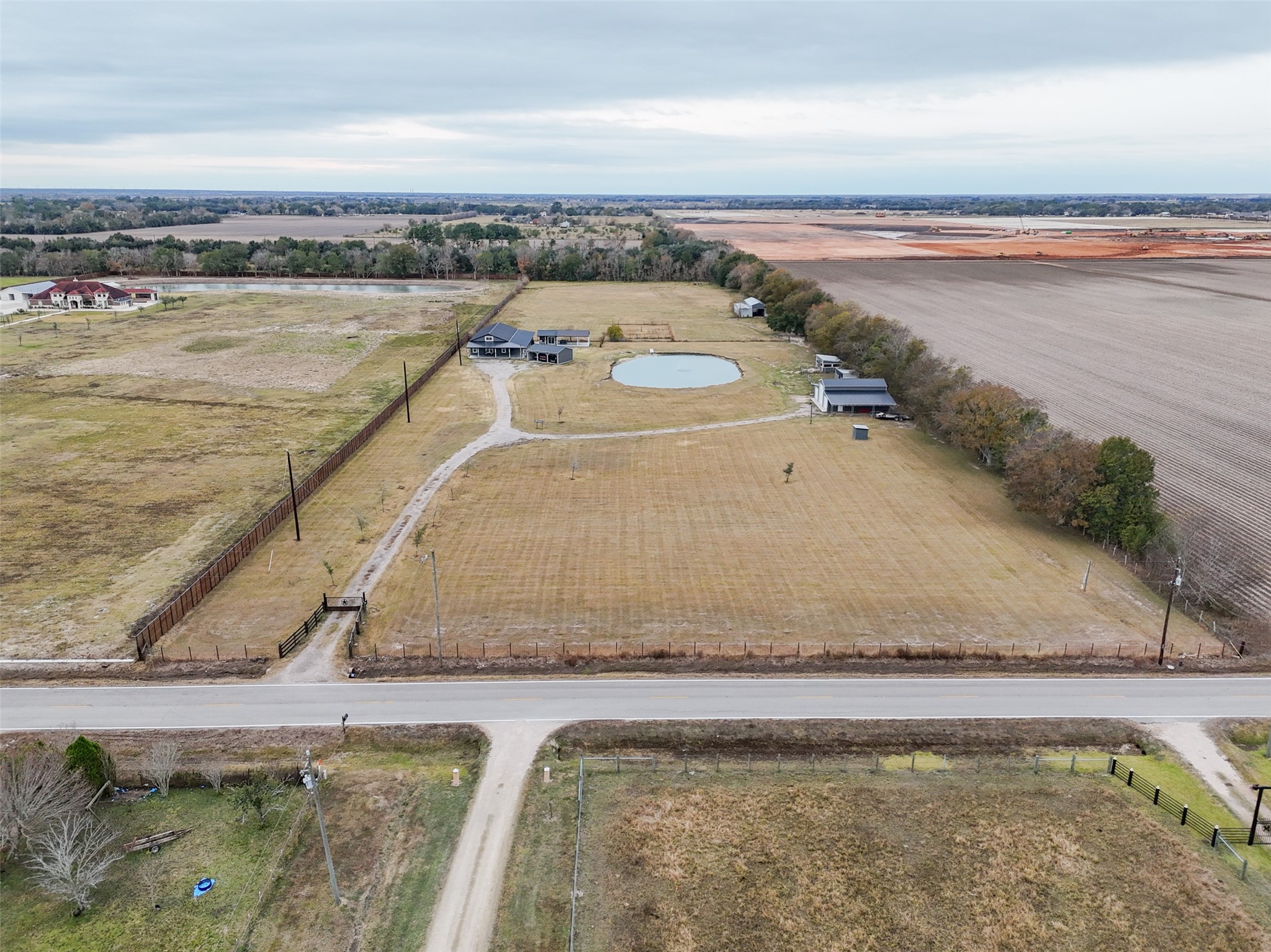10630 Padon Road Needville, TX 77461 - Photo 46 of 50 High-altitude aerial view shows the full depth of the property from the road frontage to the rear boundary. Open pasture, fencing, and the pond are centrally positioned with improvements set back from the road.