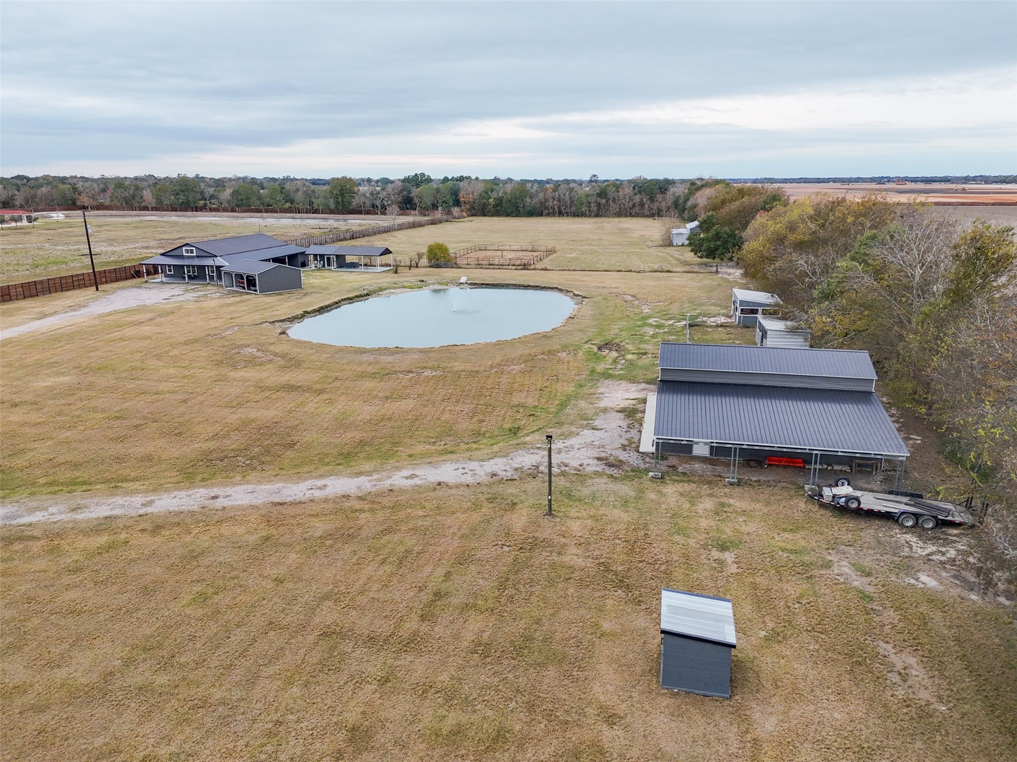 10630 Padon Road Needville, TX 77461 - Photo 47 of 50 Elevated aerial highlights the relationship between the home, pond, and outbuildings. The layout provides separation between living areas and agricultural structures.