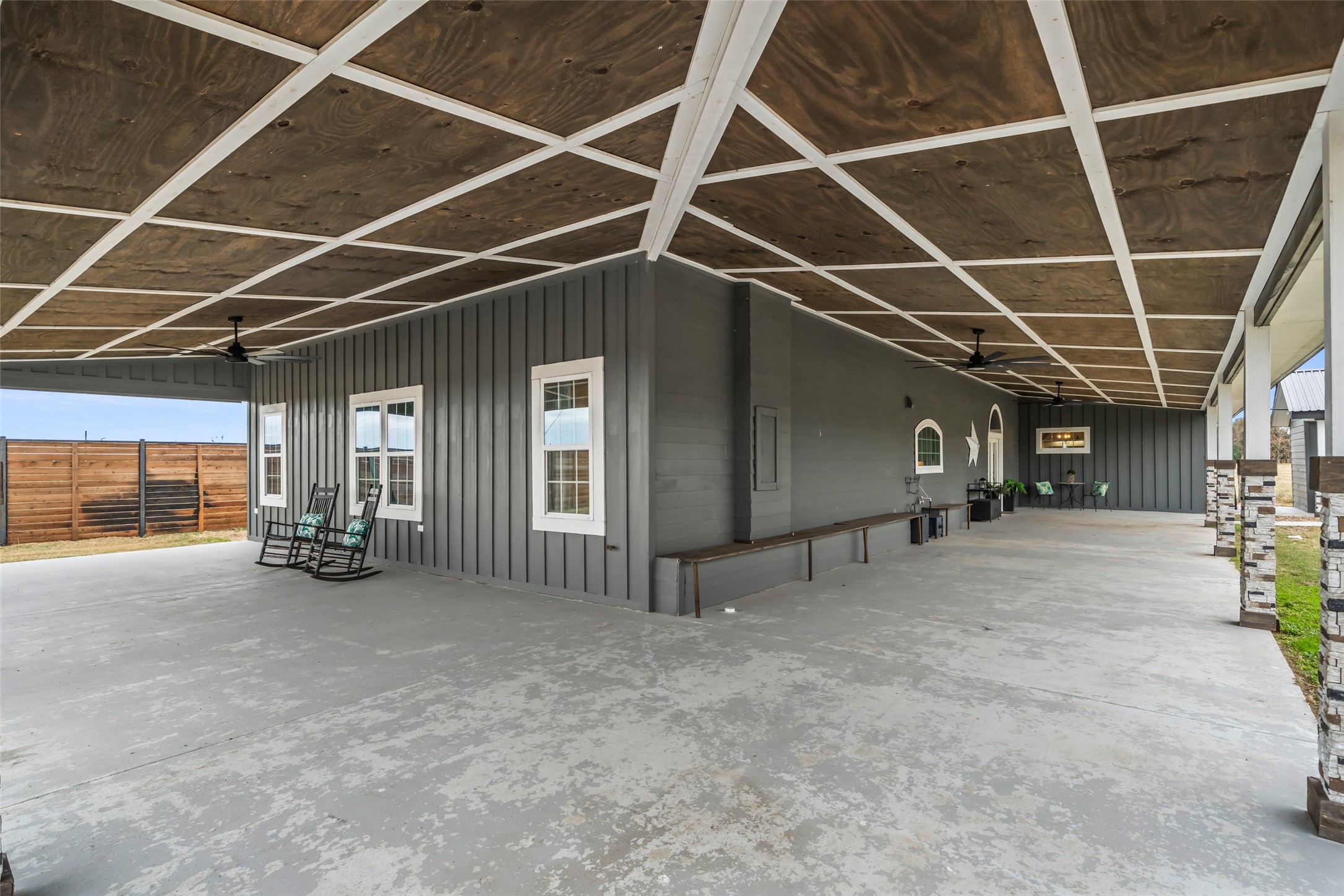 10630 Padon Road Needville, TX 77461 - Photo 7 of 50 Expansive covered patio features newly finished ceiling details, stone columns, and ceiling fans. This shaded space offers a comfortable extension of the home’s living area.