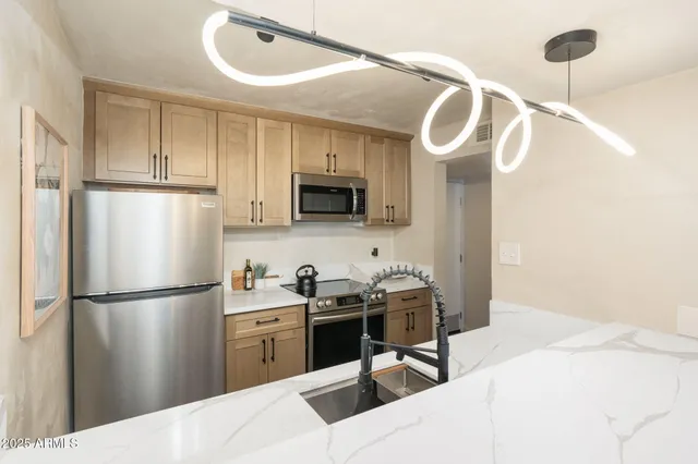 a kitchen with stainless steel appliances kitchen island a refrigerator sink and cabinets