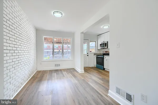 a view of a kitchen with wooden floor electronic appliances and windows