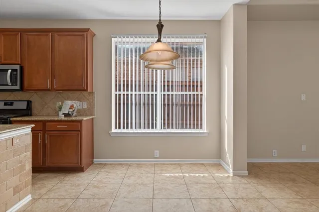 a view of an empty room with kitchen and window