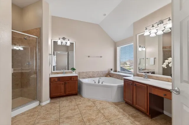 a bathroom with a tub a sink double vanity and a mirror