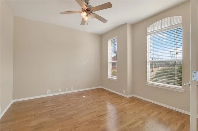a view of an empty room with a window and wooden floor