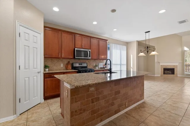 a large kitchen with granite countertop a stove a sink dishwasher a refrigerator and a oven with wooden floor