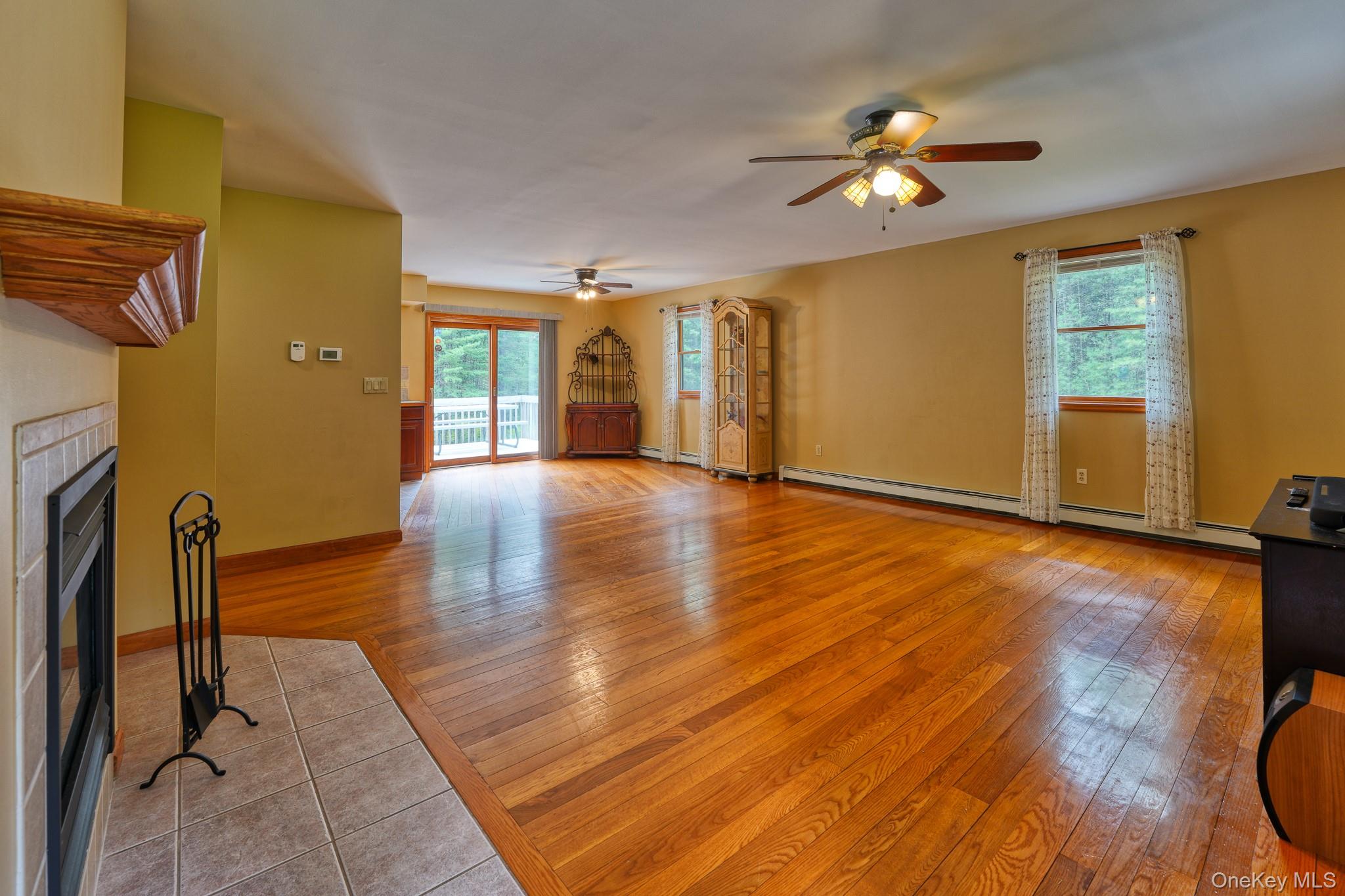 160 Barryville - Yulan Road Barryville, NY 12719 - Photo 9 of 38 Unfurnished living room with a tile fireplace, light tile patterned flooring, a ceiling fan, and baseboard heating