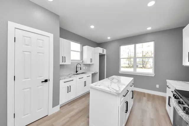 a kitchen with a sink appliances cabinets and wooden floor