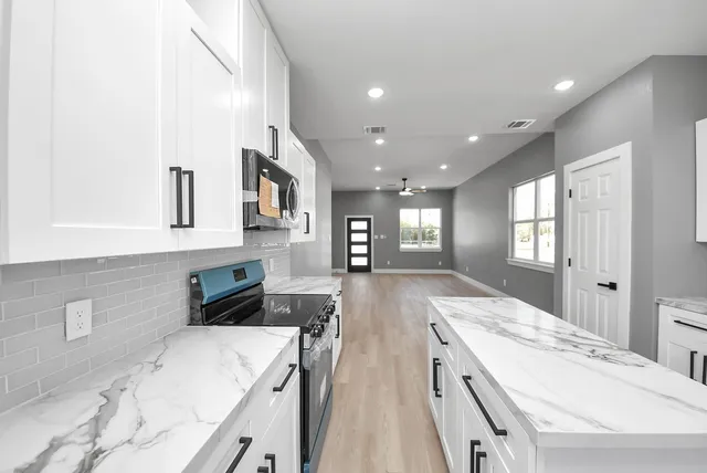 a large kitchen with stainless steel appliances a stove a sink a oven and a refrigerator