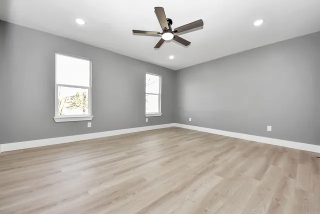 an empty room with wooden floor and windows