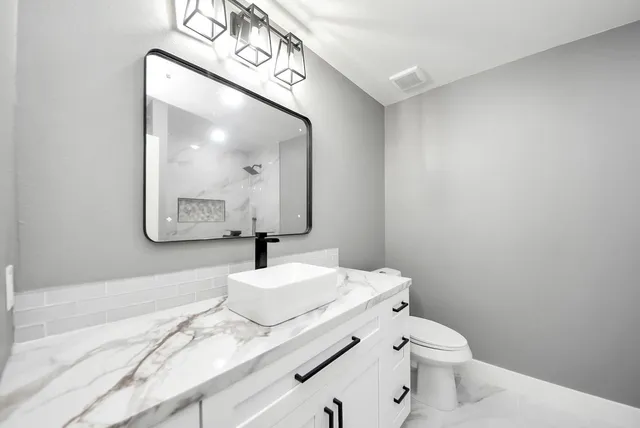 a bathroom with a granite countertop sink mirror vanity and toilet